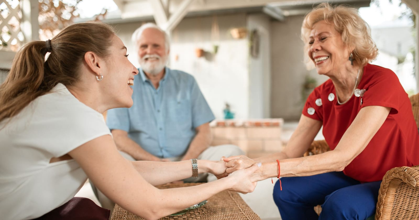 Mujer sonriendo con sus padres mayores, tomados de la mano